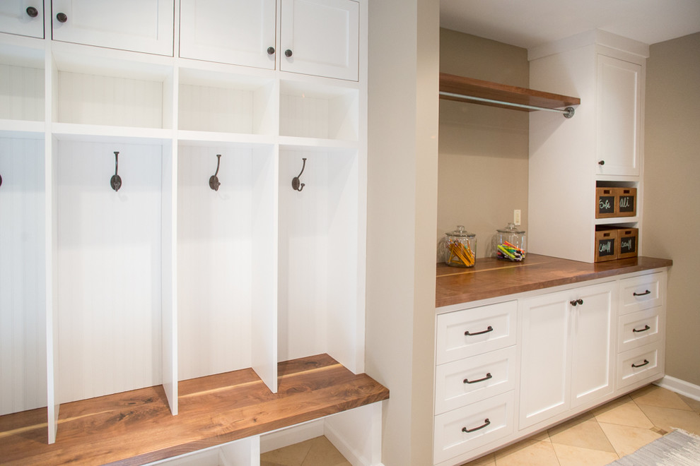 This is an example of a large transitional utility room in Philadelphia with shaker cabinets, white cabinets, wood benchtops, beige walls, ceramic floors and a side-by-side washer and dryer.