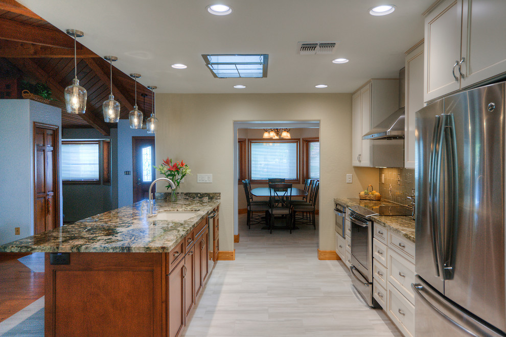 Inspiration for a large transitional galley porcelain tile eat-in kitchen remodel in Phoenix with an undermount sink, shaker cabinets, white cabinets, granite countertops, green backsplash, glass tile backsplash, stainless steel appliances and an island