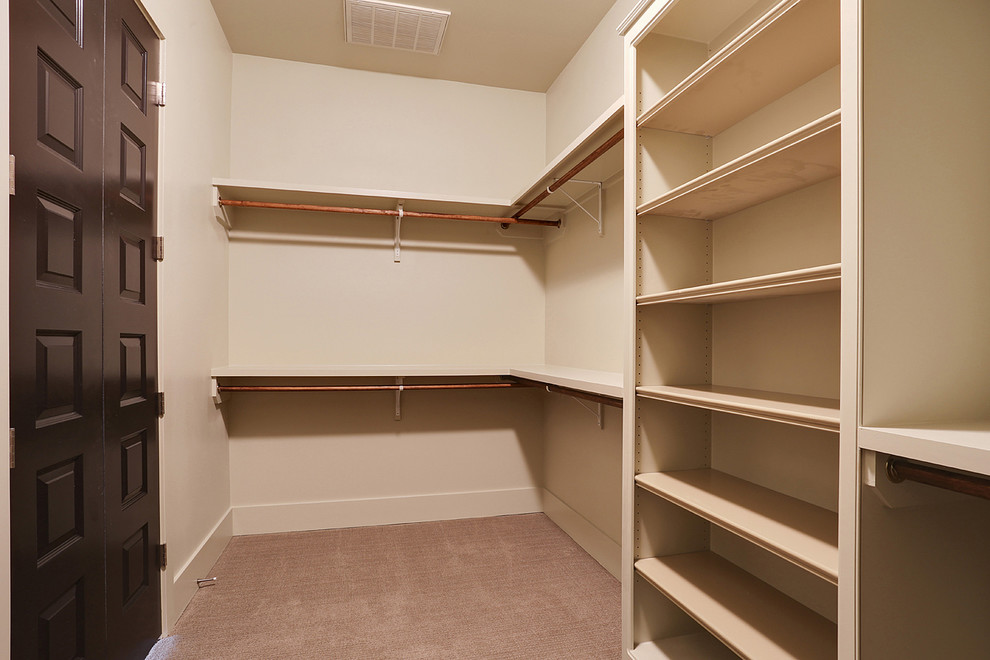 Photo of a mid-sized transitional gender-neutral walk-in wardrobe in New Orleans with beige cabinets, carpet and open cabinets.
