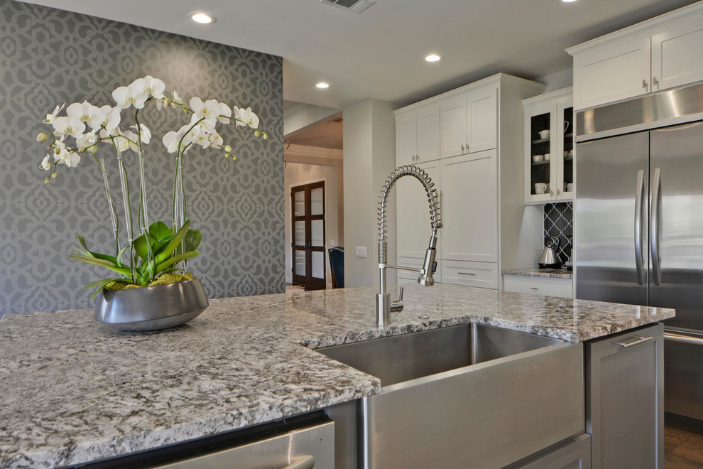 Enclosed kitchen - large transitional l-shaped dark wood floor enclosed kitchen idea in Austin with a farmhouse sink, shaker cabinets, white cabinets, granite countertops, gray backsplash, mosaic tile backsplash, stainless steel appliances and an island