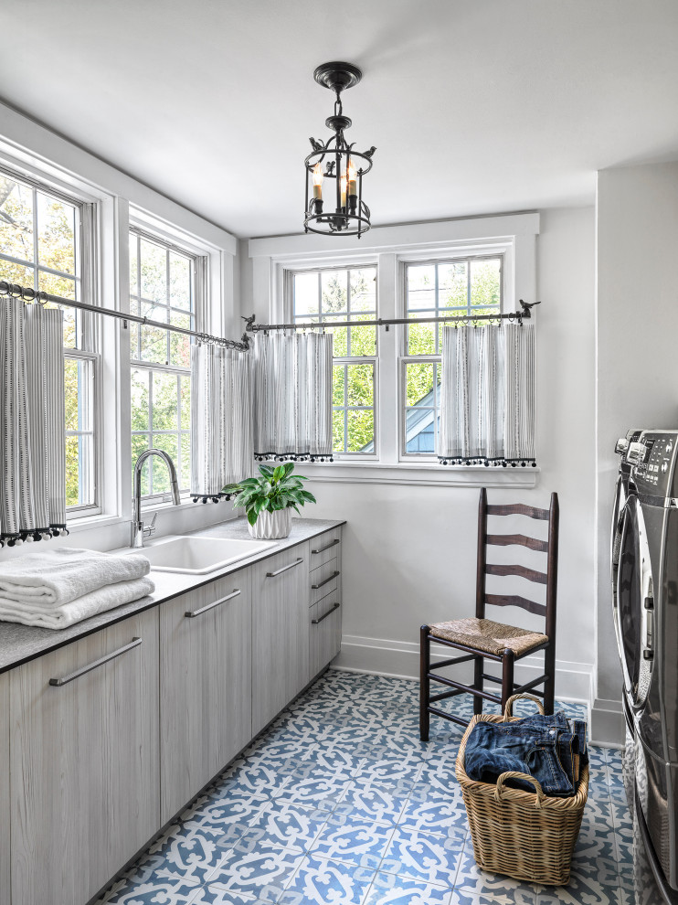 Design ideas for a mid-sized transitional galley dedicated laundry room in St Louis with a drop-in sink, flat-panel cabinets, light wood cabinets, laminate benchtops, white walls, terra-cotta floors, a side-by-side washer and dryer, blue floor and grey benchtop.