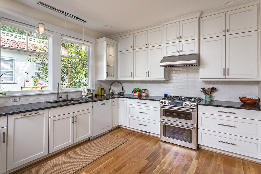 Inspiration for a mid-sized traditional u-shaped eat-in kitchen in Raleigh with a single-bowl sink, flat-panel cabinets, white cabinets, granite benchtops, yellow splashback, ceramic splashback, stainless steel appliances, medium hardwood floors and a peninsula.