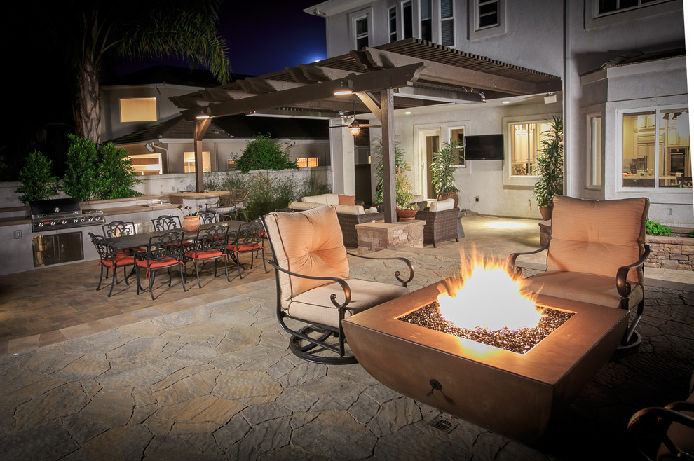 This is an example of a large traditional backyard patio in San Diego with a fire feature, concrete pavers and a pergola.