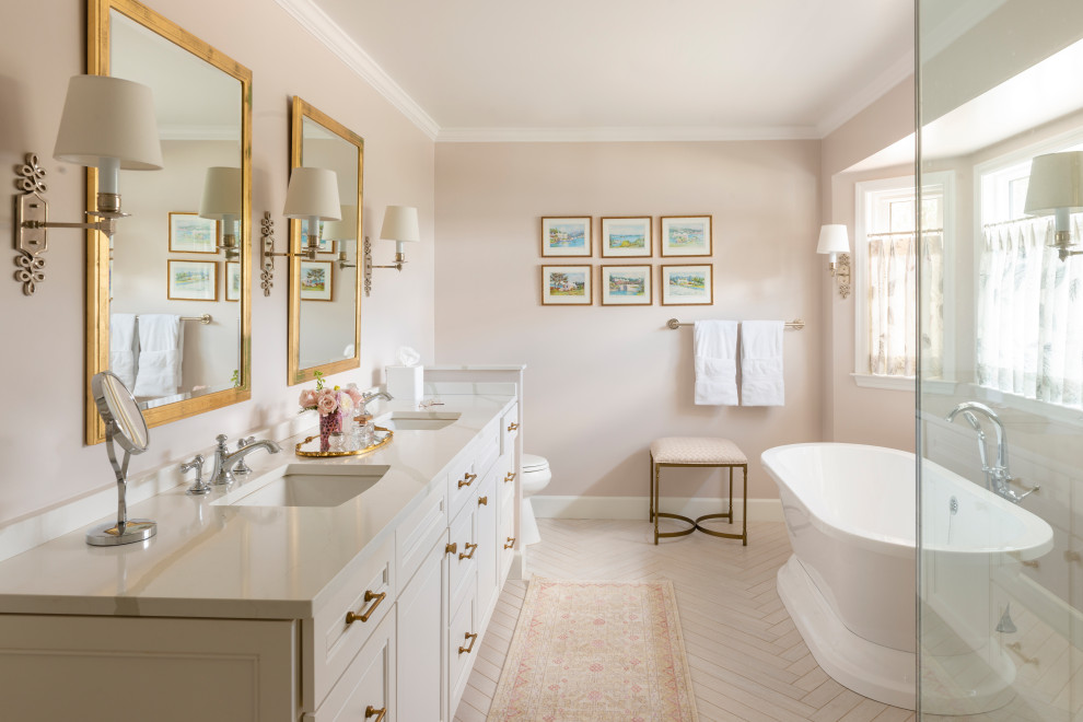 На фото: главная ванная комната среднего размера в классическом стиле с белыми фасадами, отдельно стоящей ванной, раздельным унитазом, розовыми стенами, душем с распашными дверями, тумбой под две раковины и встроенной тумбой