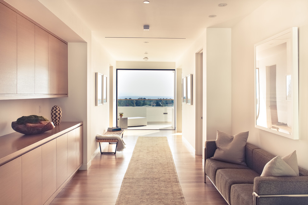 This is an example of a large contemporary hallway in Los Angeles with white walls and medium hardwood floors.