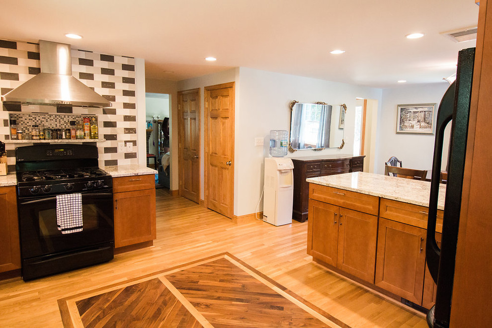 Mid-sized transitional u-shaped medium tone wood floor eat-in kitchen photo in Boston with an undermount sink, recessed-panel cabinets, medium tone wood cabinets, granite countertops, multicolored backsplash, subway tile backsplash, black appliances and a peninsula