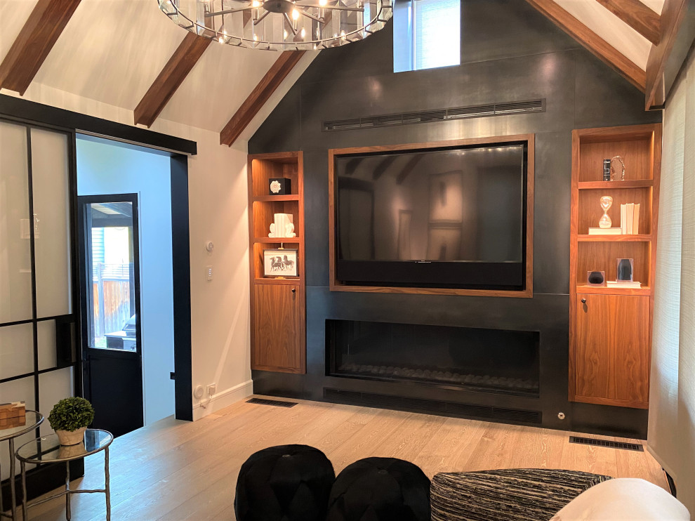 Aménagement d'une salle de séjour contemporaine de taille moyenne et fermée avec un mur noir, parquet clair, une cheminée ribbon, un manteau de cheminée en métal, un téléviseur encastré et un plafond voûté.