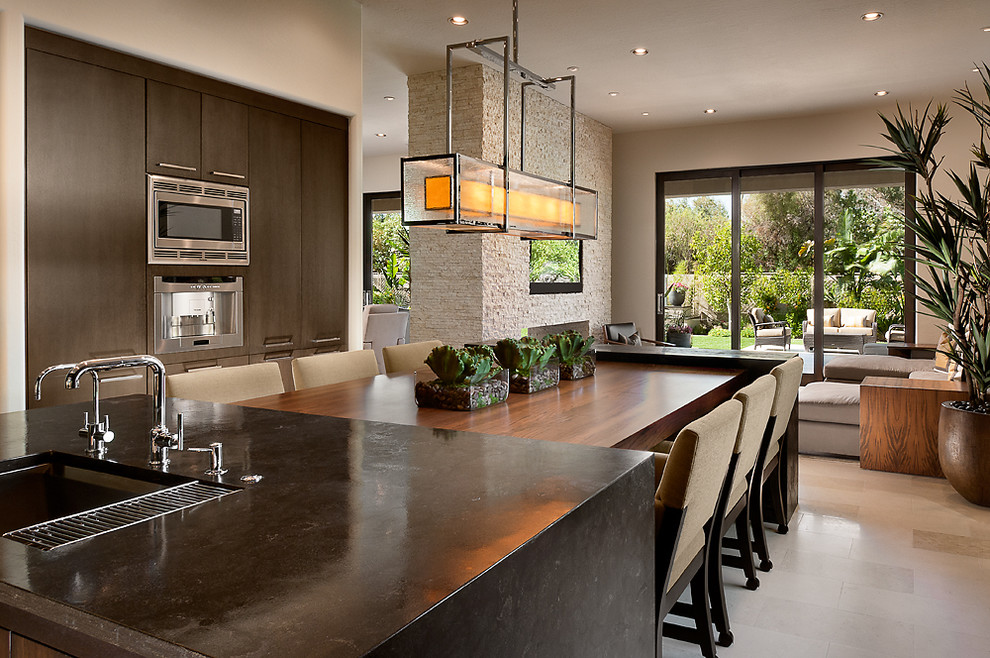 Contemporary open plan kitchen in Phoenix with stainless steel appliances, limestone benchtops, flat-panel cabinets and dark wood cabinets.