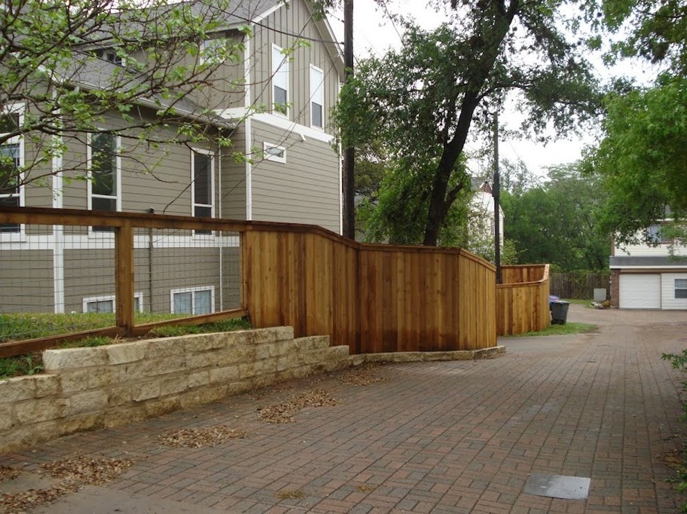Design ideas for a large traditional side yard full sun driveway for winter in Austin with a retaining wall and brick pavers.
