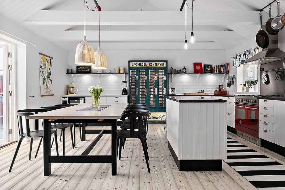 Design ideas for a large scandinavian l-shaped eat-in kitchen in Stockholm with white cabinets, coloured appliances, light hardwood floors, with island, raised-panel cabinets and laminate benchtops.
