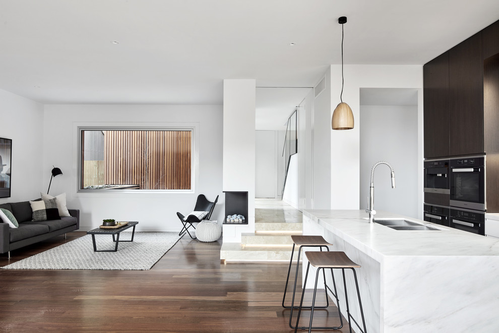 Contemporary open concept family room in Melbourne with white walls, dark hardwood floors, a corner fireplace, a metal fireplace surround and brown floor.