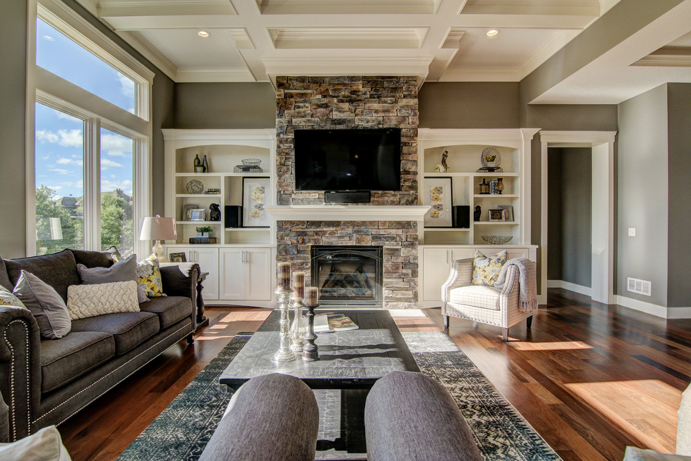 This is an example of a large traditional open concept family room in Minneapolis with grey walls, medium hardwood floors, a standard fireplace and a wall-mounted tv.