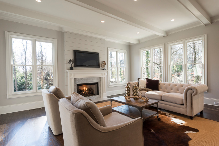 Design ideas for a mid-sized enclosed family room in Atlanta with grey walls, medium hardwood floors, a standard fireplace, a stone fireplace surround and a wall-mounted tv.