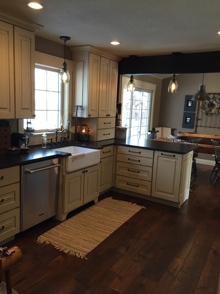 Enclosed kitchen - mid-sized rustic l-shaped dark wood floor enclosed kitchen idea in Minneapolis with a farmhouse sink, raised-panel cabinets, distressed cabinets, granite countertops, black backsplash, stainless steel appliances and an island