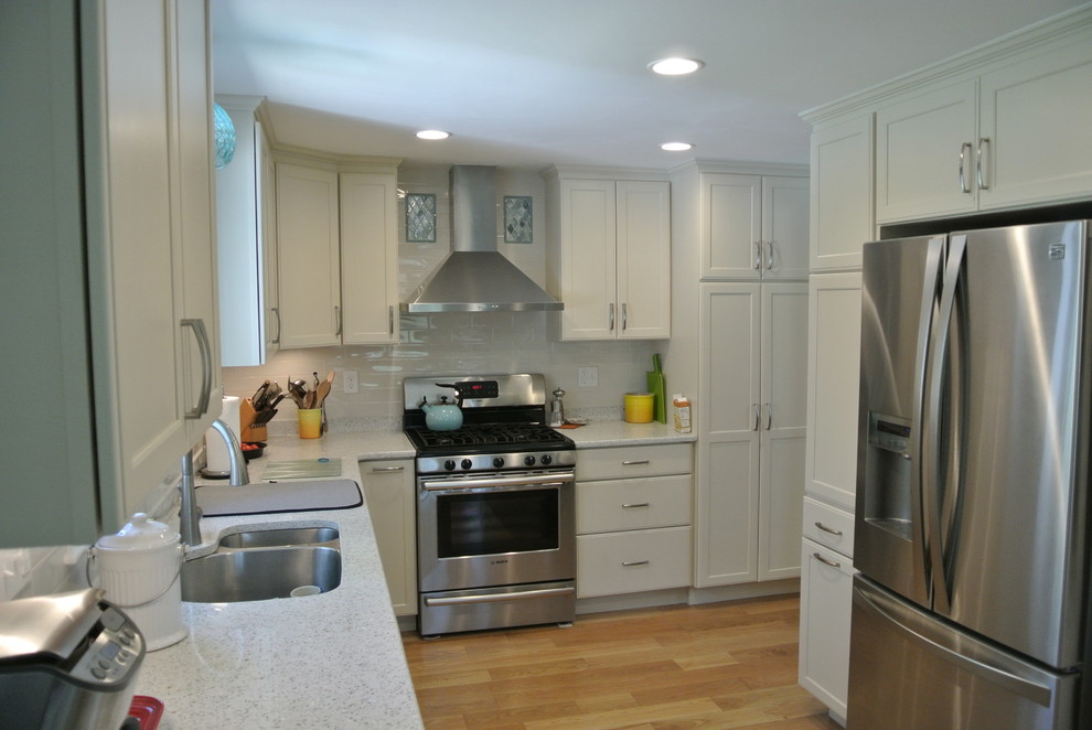 Eat-in kitchen - transitional l-shaped medium tone wood floor eat-in kitchen idea in Boston with an undermount sink, shaker cabinets, white cabinets, recycled glass countertops, white backsplash, subway tile backsplash, stainless steel appliances, a peninsula and white countertops