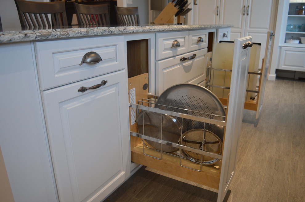 Inspiration for a large transitional u-shaped ceramic tile and gray floor home design remodel with a farmhouse sink, raised-panel cabinets, white cabinets, quartz countertops, gray backsplash, glass tile backsplash, stainless steel appliances and an island
