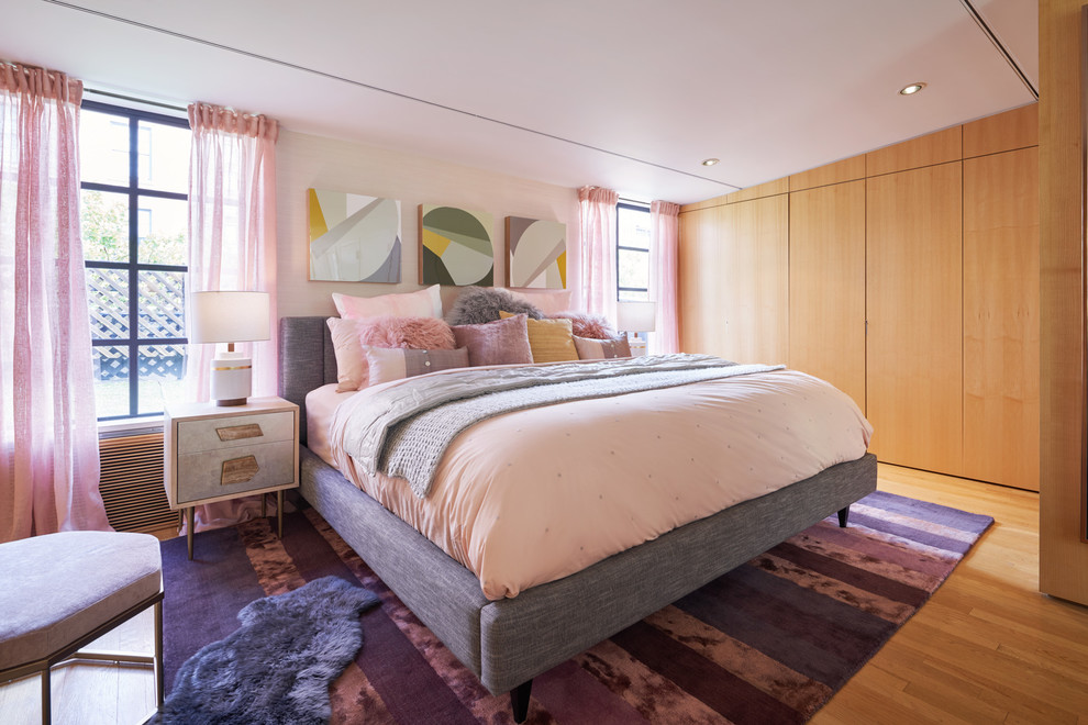 Photo of a midcentury bedroom in New York with pink walls, medium hardwood floors and no fireplace.