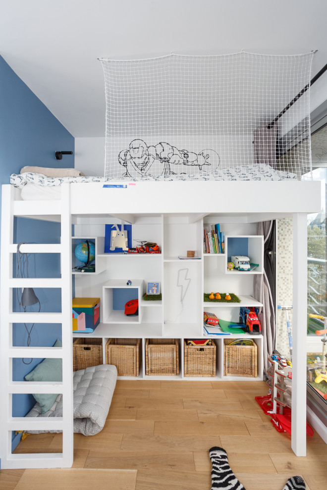 This is an example of a mid-sized modern kids' bedroom for kids 4-10 years old and boys in Paris with multi-coloured walls, light hardwood floors, beige floor and wallpaper.