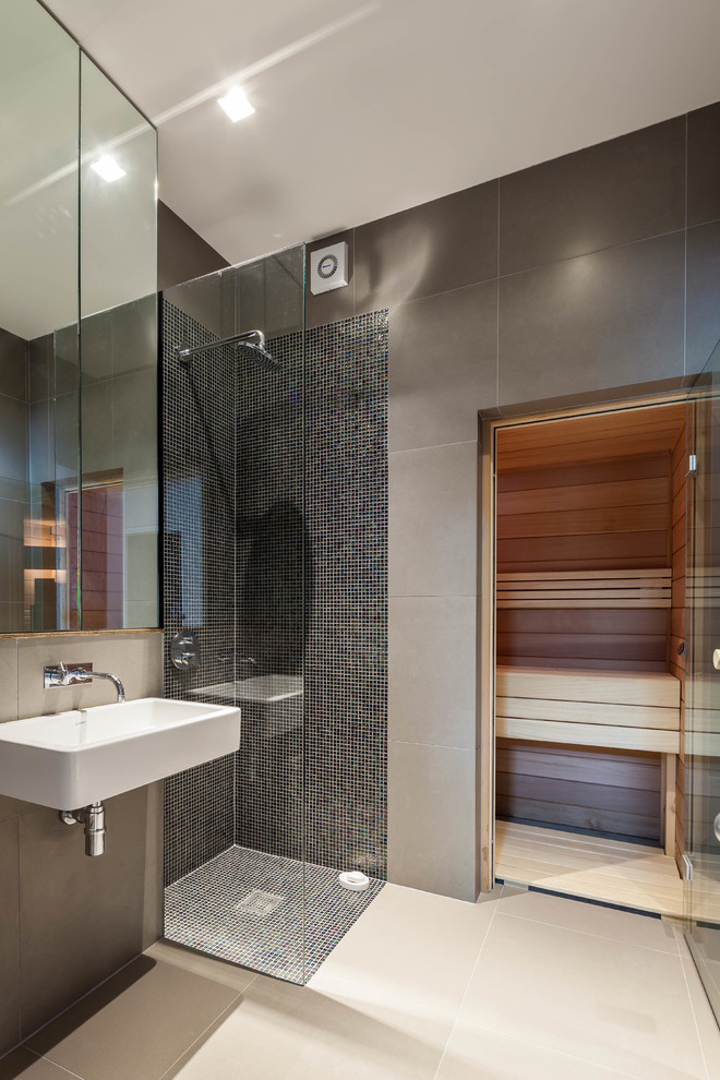 This is an example of a large contemporary master bathroom in London with a wall-mount sink, an open shower, grey walls, flat-panel cabinets, gray tile, ceramic tile, ceramic floors and an open shower.