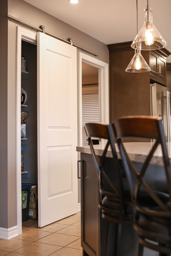 Mid-sized transitional u-shaped enclosed kitchen photo in Toronto with an undermount sink, recessed-panel cabinets, dark wood cabinets, quartz countertops, white backsplash, porcelain backsplash, stainless steel appliances and an island