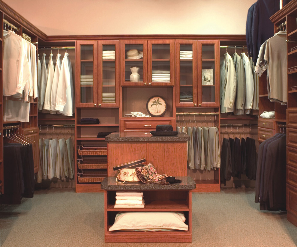 Design ideas for a mid-sized traditional men's walk-in wardrobe in Orange County with raised-panel cabinets, dark wood cabinets and carpet.