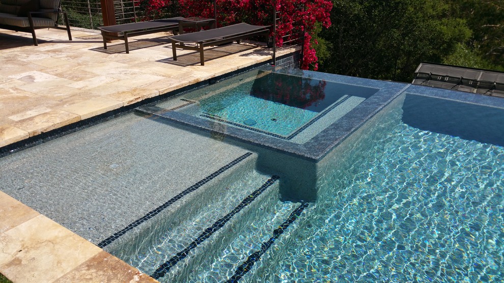 This is an example of a large modern backyard rectangular infinity pool in San Francisco with a pool house and tile.