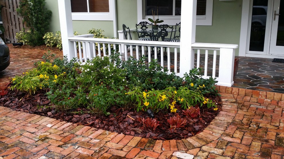 This is an example of a mid-sized tropical front yard full sun formal garden in Miami with a water feature and brick pavers.