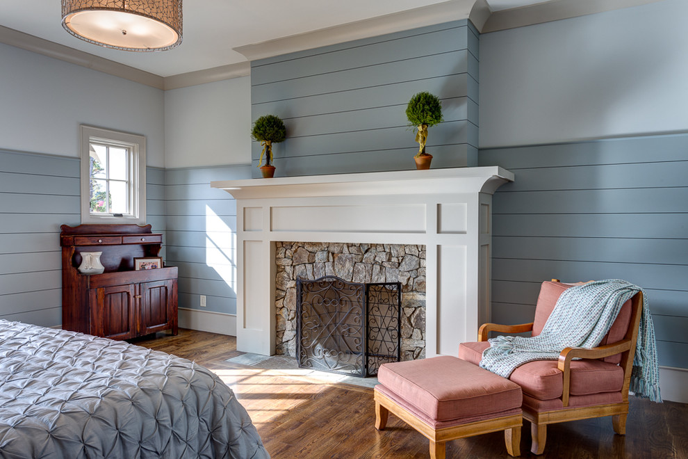 Mid-sized beach style master bedroom in Other with blue walls, dark hardwood floors, a standard fireplace and a stone fireplace surround.