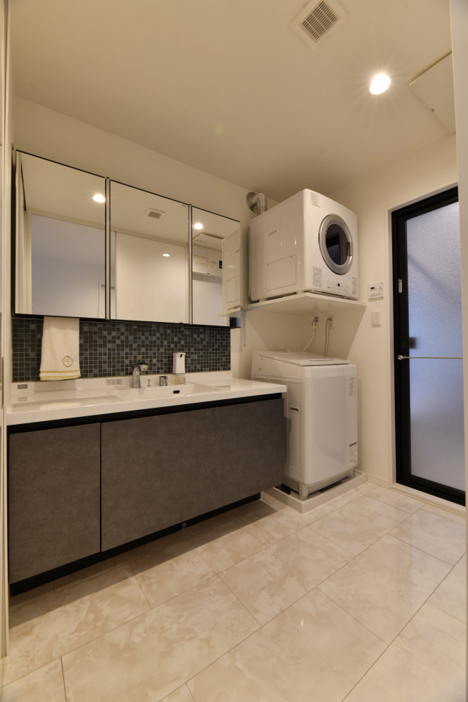 Photo of a mid-sized modern single-wall utility room in Fukuoka with an integrated sink, flat-panel cabinets, grey cabinets, solid surface benchtops, white walls, a stacked washer and dryer, beige floor, white benchtop, wallpaper and wallpaper.