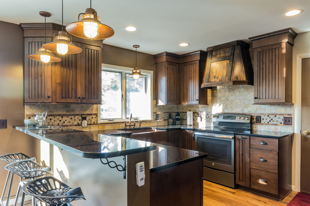 Photo of a mid-sized country u-shaped eat-in kitchen in Detroit with a farmhouse sink, recessed-panel cabinets, dark wood cabinets, quartz benchtops, beige splashback, metal splashback, stainless steel appliances, medium hardwood floors and a peninsula.