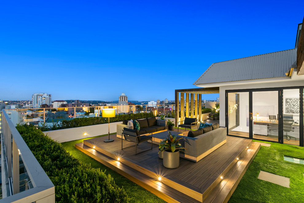 This is an example of a large modern courtyard patio in Sydney with an outdoor kitchen, brick pavers and a pergola.