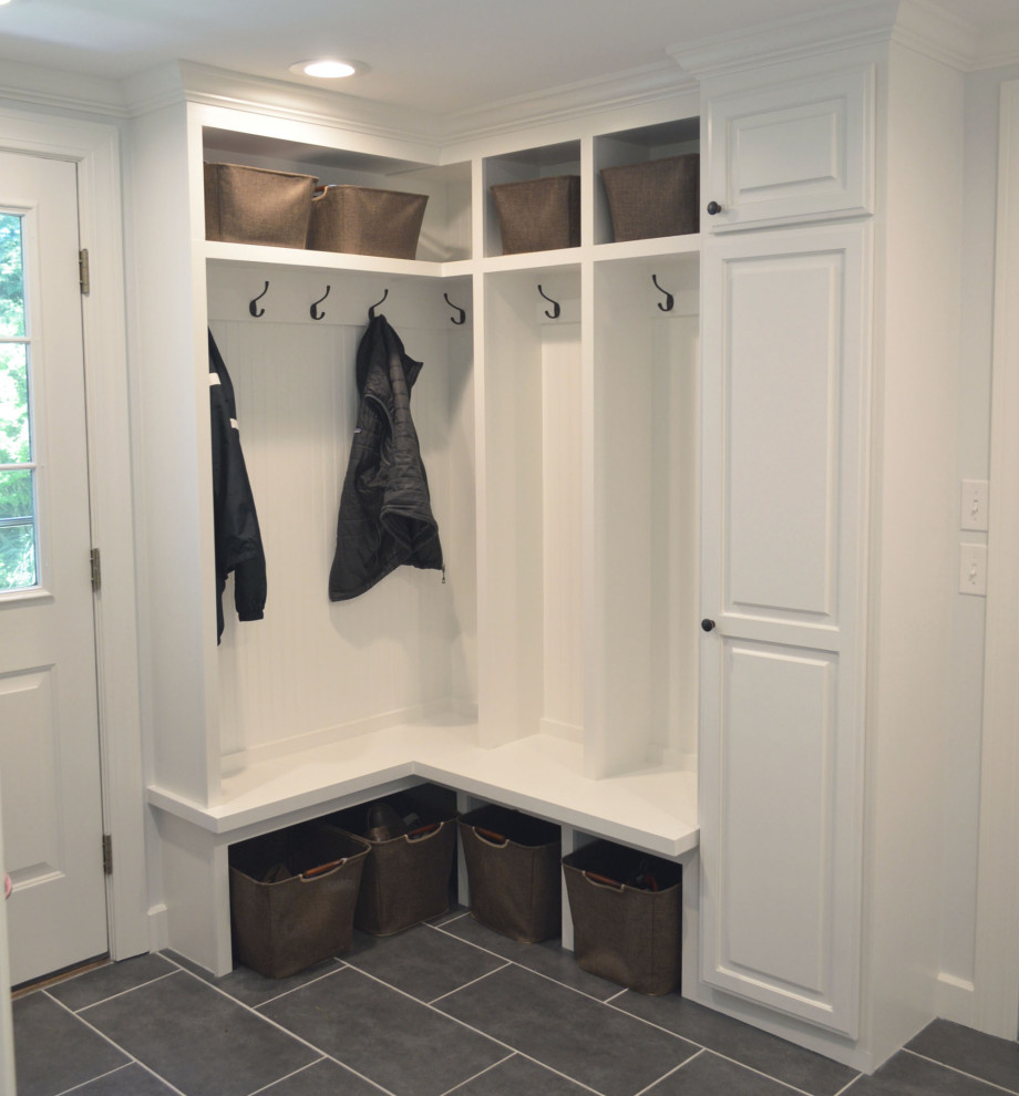 This is an example of a small traditional mudroom with white walls, porcelain floors and grey floor.