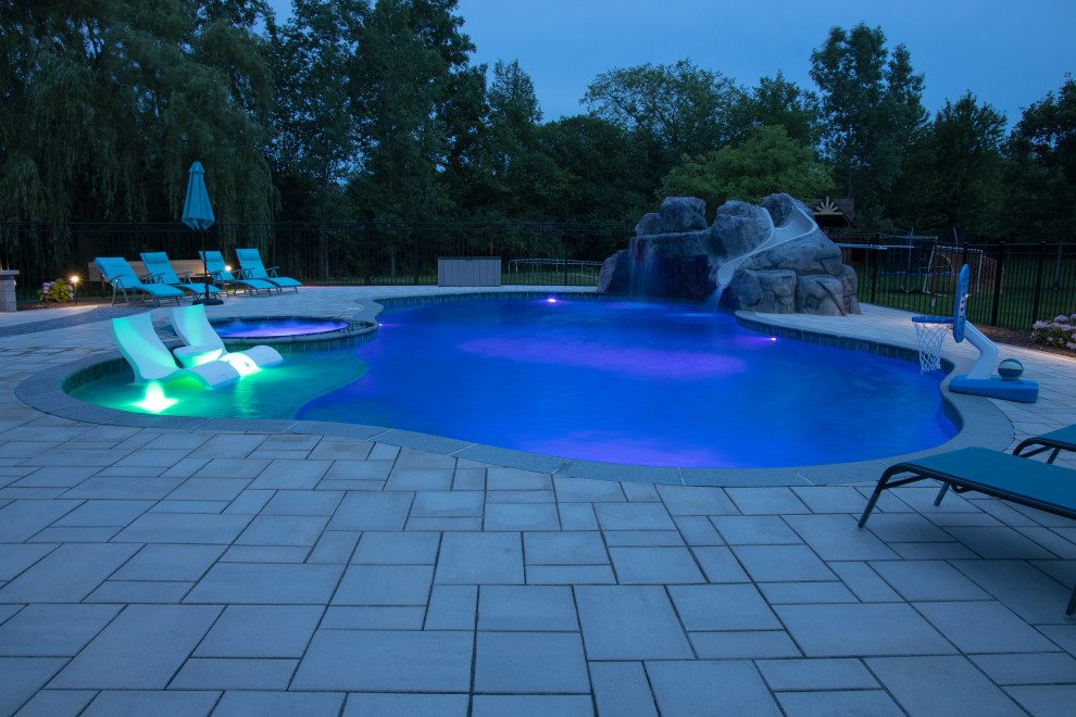 Immagine di un'ampia piscina naturale moderna personalizzata dietro casa con un acquascivolo e cemento stampato