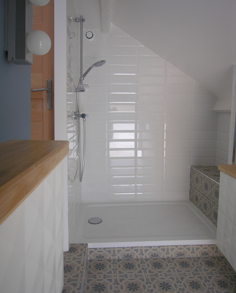 Photo of a mid-sized transitional 3/4 bathroom in Paris with an alcove shower, subway tile, cement tiles, a vessel sink, wood benchtops, open cabinets, white tile, white walls, blue floor, an open shower and brown benchtops.