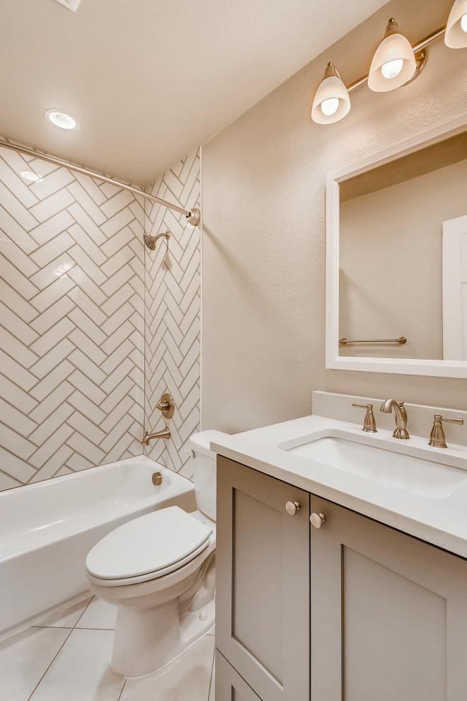 Photo of a mid-sized contemporary 3/4 bathroom in Denver with recessed-panel cabinets, grey cabinets, an alcove tub, a shower/bathtub combo, white tile, ceramic tile, brown walls, an undermount sink, quartzite benchtops, white floor, a shower curtain, white benchtops, a single vanity, a built-in vanity and wallpaper.