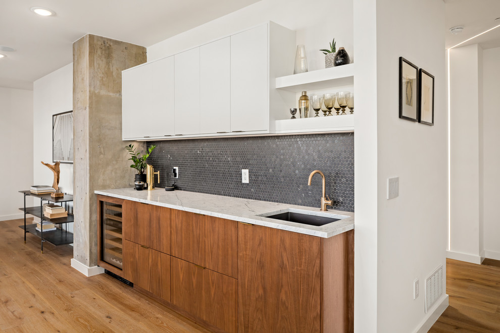 Contemporary single-wall wet bar in Nashville with an undermount sink, flat-panel cabinets, medium wood cabinets, black splashback, mosaic tile splashback, medium hardwood floors, brown floor and white benchtop.