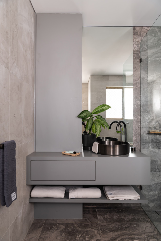 Foto på ett mellanstort funkis grå en-suite badrum, med grå skåp, ett fristående badkar, grå kakel, porslinskakel, klinkergolv i porslin, laminatbänkskiva, grått golv och dusch med gångjärnsdörr