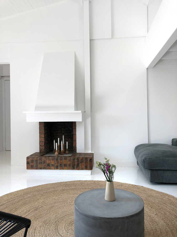 パリにあるお手頃価格の広いコンテンポラリースタイルのおしゃれなオープンリビング (ライブラリー、白い壁、塗装フローリング、標準型暖炉、レンガの暖炉まわり、白い床、テレビなし) の写真