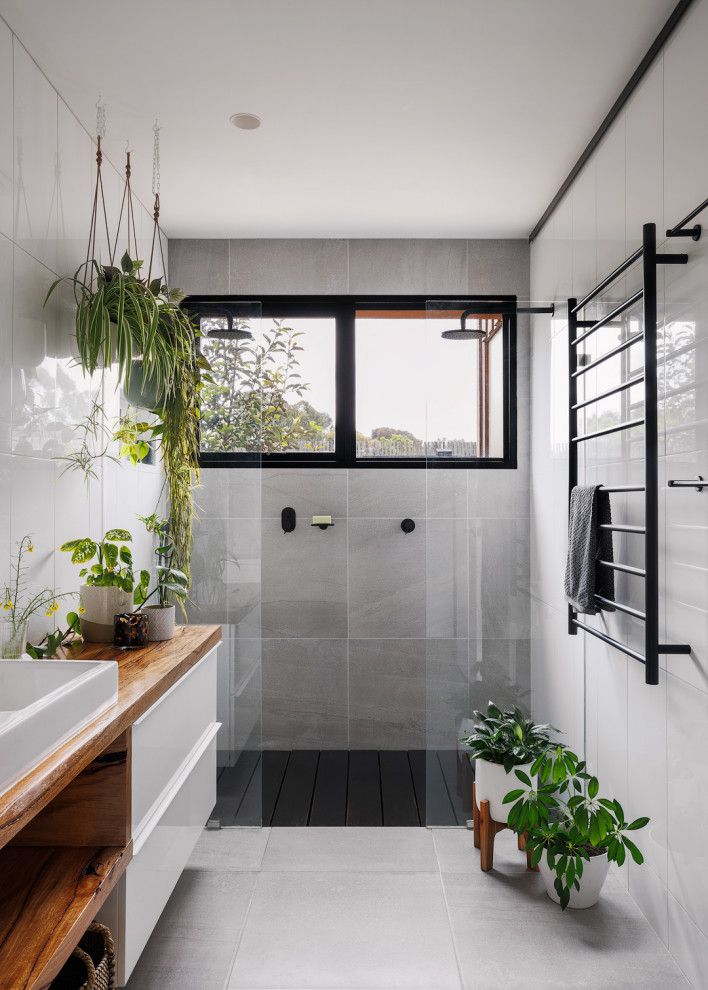 Design ideas for a mid-sized contemporary bathroom in Melbourne with white cabinets, a double shower, white tile, porcelain floors, wood benchtops, grey floor, an open shower, a single vanity, a floating vanity, flat-panel cabinets, a drop-in sink and brown benchtops.