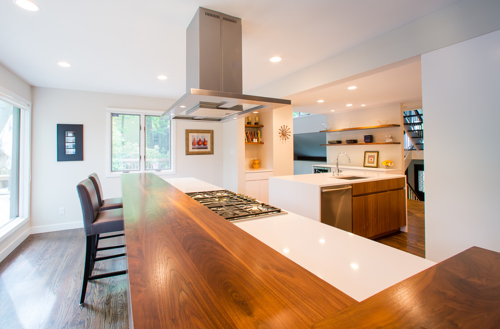 This is an example of a mid-sized contemporary u-shaped eat-in kitchen in DC Metro with an undermount sink, flat-panel cabinets, white cabinets, solid surface benchtops, stainless steel appliances, dark hardwood floors, multiple islands, brown floor and white benchtop.