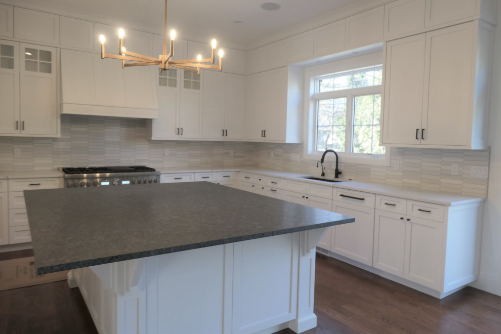 Photo of a country kitchen in Detroit with an undermount sink, shaker cabinets, white cabinets, quartzite benchtops, white splashback, subway tile splashback, dark hardwood floors, with island and white benchtop.