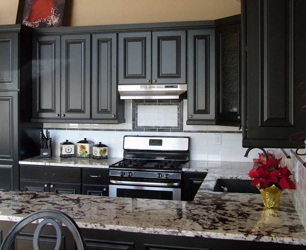 Mid-sized transitional u-shaped light wood floor open concept kitchen photo in Denver with an undermount sink, beaded inset cabinets, black cabinets, marble countertops, white backsplash, subway tile backsplash, stainless steel appliances and a peninsula