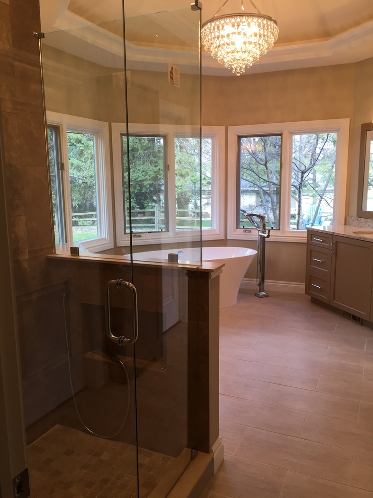 Design ideas for a large contemporary master bathroom in Detroit with shaker cabinets, a freestanding tub, a corner shower, an undermount sink, quartzite benchtops, brown cabinets, beige walls, porcelain floors, beige floor and a hinged shower door.