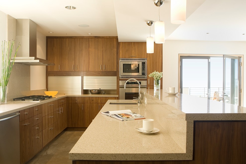 This is an example of a large contemporary eat-in kitchen in San Francisco with stainless steel appliances, an undermount sink, flat-panel cabinets, dark wood cabinets, quartz benchtops, white splashback, concrete floors and with island.