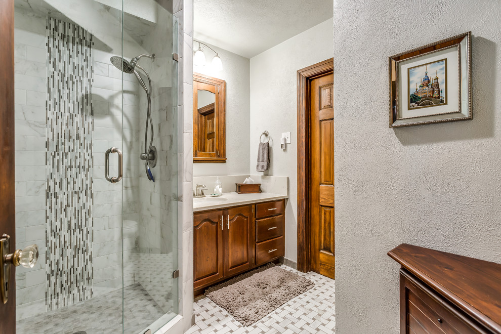 Photo of a mid-sized traditional 3/4 bathroom in Dallas with raised-panel cabinets, dark wood cabinets, a corner shower, gray tile, marble, grey walls, marble floors, an undermount sink, marble benchtops, multi-coloured floor, a hinged shower door and grey benchtops.