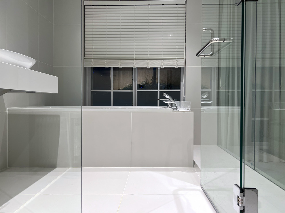 Mid-sized modern master bathroom in Tokyo with white cabinets, a drop-in tub, a shower/bathtub combo, gray tile, porcelain tile, porcelain floors, a pedestal sink, grey floor, a hinged shower door, white benchtops, a single vanity and a floating vanity.