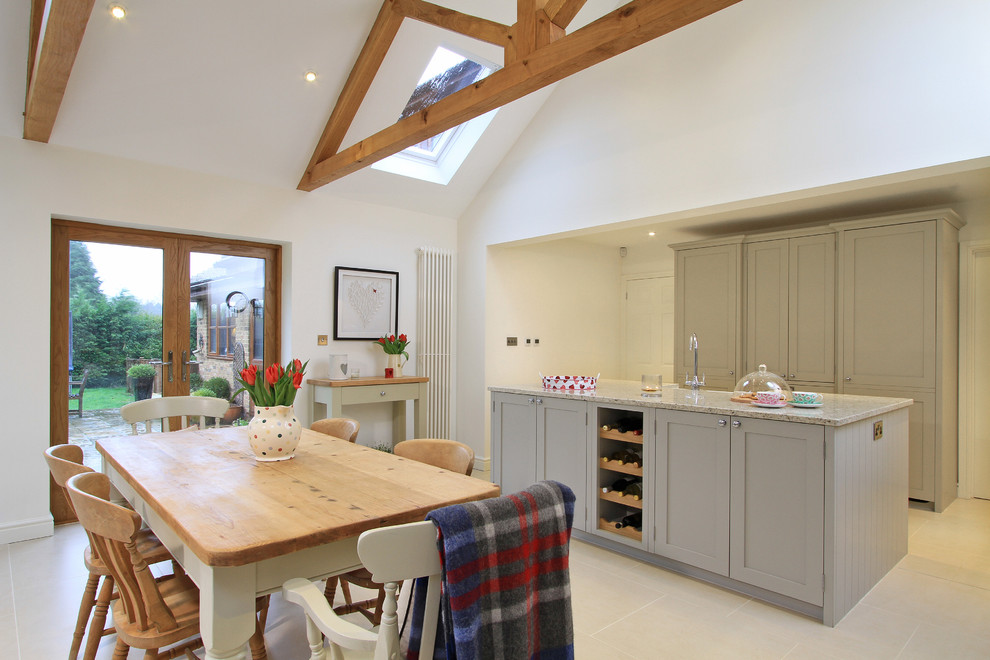 Photo of a large traditional l-shaped eat-in kitchen in Hampshire with a farmhouse sink, shaker cabinets, grey cabinets, granite benchtops, ceramic splashback, coloured appliances, porcelain floors and with island.