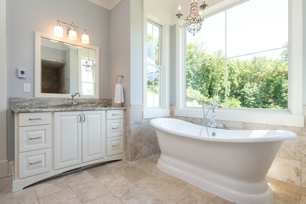 Large transitional master bathroom in Other with raised-panel cabinets, white cabinets, a freestanding tub, a one-piece toilet, beige tile, porcelain tile, grey walls, travertine floors, an undermount sink, granite benchtops and beige floor.