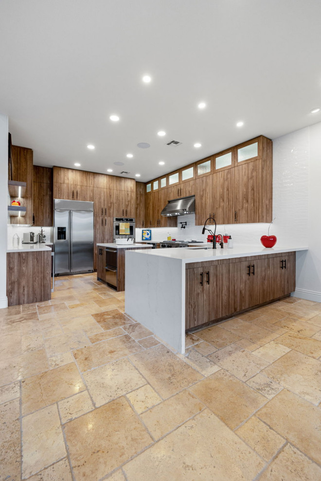 Example of a mountain style l-shaped slate floor and beige floor enclosed kitchen design with a single-bowl sink, flat-panel cabinets, medium tone wood cabinets, quartzite countertops, white backsplash, glass sheet backsplash, stainless steel appliances, a peninsula and white countertops