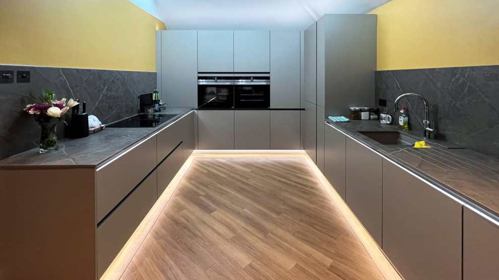 Inspiration for a mid-sized contemporary u-shaped separate kitchen in London with an undermount sink, flat-panel cabinets, grey cabinets, quartzite benchtops, light hardwood floors and grey benchtop.